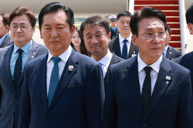 더불어민주당 정청래 대표와 김민석 총리가 18일 성남 서울공항에서 G7 정상회의와 유럽 순방을 마치고 귀국한 이재명 대통령과 인사를 나눈 뒤 의전 차량 이동을 기다리고 있다. 연합뉴스