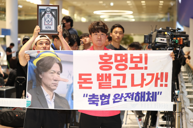 2026 북중미 월드컵 32강 진출에 실패해 한국 축구 국가대표팀에서 사퇴한 홍명보 전 감독이 입국하는 30일 인천국제공항 제2여객터미널을 찾은 팬들이 항의 현수막을 들어올리고 있다. 연합뉴스