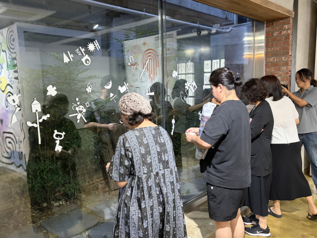 전시장을 찾은 관람객들이 전시장에 비치된 스티커를 활용해 창문에 자신만의 그림을 완성하고 있다. 김은영 기자 key66@