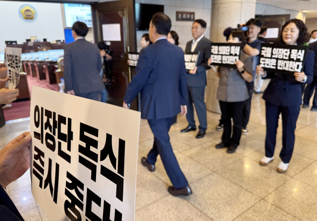 경남도의회 더불어민주당 의원단이 6일 오후 의장·부의장을 뽑는 13대 의회 전반기 첫 임시회 직전 본회의장 앞에서 '의장단 독식 즉시 중단'을 요구하는 항의 피케팅을 하는 가운데 국민의힘 도의원들이 본회의장으로 입장하고 있다. 연합뉴스