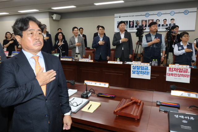 9일 정부세종청사 최저임금위원회에서 열린 제13차 전원회의에서 권순원 위원장과 위원들이 국기에 경례하고 있다. 연합뉴스