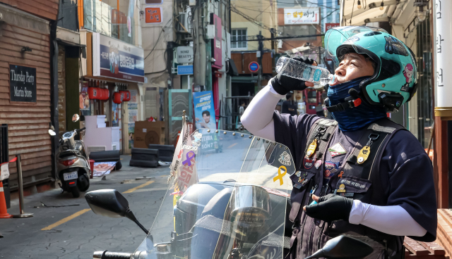 폭염이 계속된 15일 부산 부산진구 일원에서 공공운수노조 라이더유니온본부 이상진 부산지회장이 배달 중 잠시 도로에서 휴식을 취하고 있다. 김종진 기자 kjj1761@