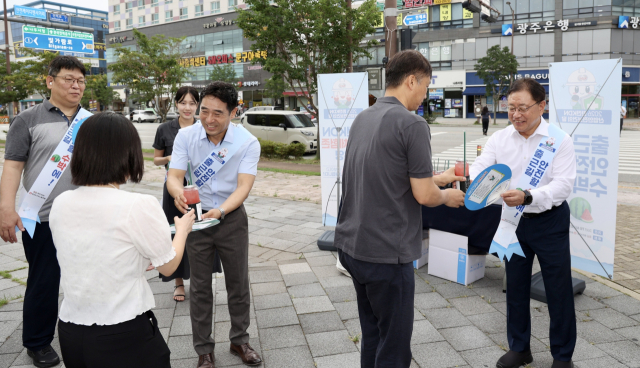 ‘안전 캠페인’에서 안전구호를 두르고 출근길 시민에게 부채와 음료를 전달하고 있는 한전KDN 박상형 사장(오른쪽)과 최은식 노조위원장. 한전KDN 제공