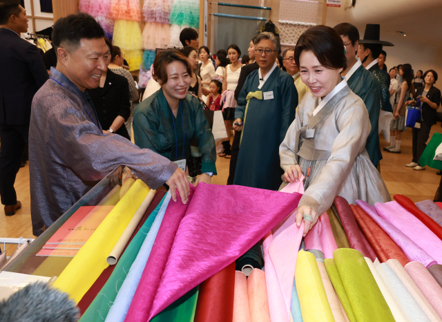 김혜경 여사가 14일 서울 중구 동대문디자인플라자에서 열린 한복박람회 '2026 한복상점'에서 원단을 보고 있다. 연합뉴스