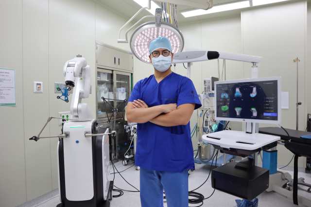 센텀종합병원 관절센터 박재홍 과장이 최첨단 인공관절 수술 로봇 ‘큐비스 조인트’ 앞에 서 있다. 박 과장은 “인공관절 로봇수술은 의사가 원하는 정도의 밸런스와 수치를 객관적으로 바로 확인하고 바로 수정할 수 있다”며 “통증에 시달리던 환자들이 인공관절 덕분에 걷기가 편해졌다고 이야기할 때 보람을 느낀다”고 말했다. 센텀종합병원 제공