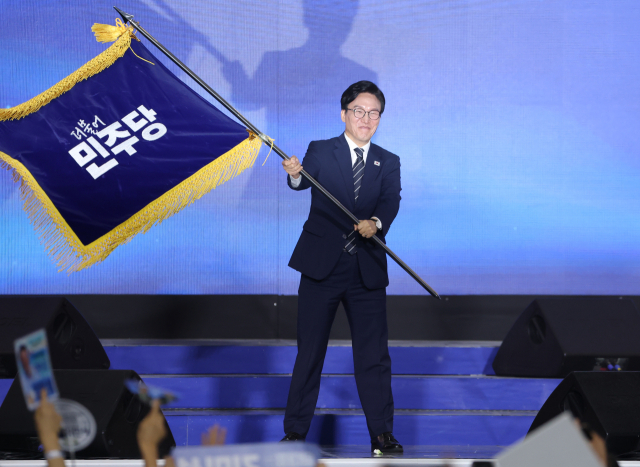 더불어민주당 당 대표에 출마한 김민석 전 총리가 17일 대전 컨벤션센터에서 열린 제3회 더불어민주당 정기 전국당원대회에서 당 대표 당선을 확정한 뒤 당기를 흔들고 있다. 연합뉴스