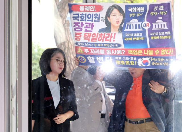 용혜인 성평등가족부 장관 후보자가 11일 서울 서대문구에 마련된 인사청문회 준비 사무실로 출근할 때 펼침막을 든 한 시민의 항의를 받고 있다. 연합뉴스
