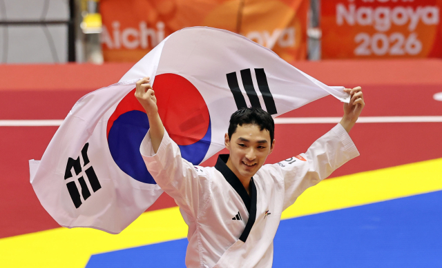 1일 일본 아이치현 도요하시 체육관에서 열린 2026 아이치·나고야 아시안게임 태권도 남자 품새 결승 경기. 1위를 차지한 윤규성이 태극기를 들고 경기장을 뛰고 있다. 연합뉴스