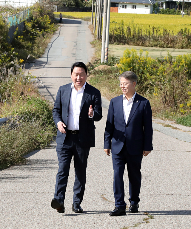 최태원 SK그룹 회장(왼쪽)이 9일 광주 탄약고 부지를 방문해 민형배 전남광주통합특별시장(오른쪽)과 함께 현장을 둘러보며 대화를 나누고 있다. SK그룹 제공