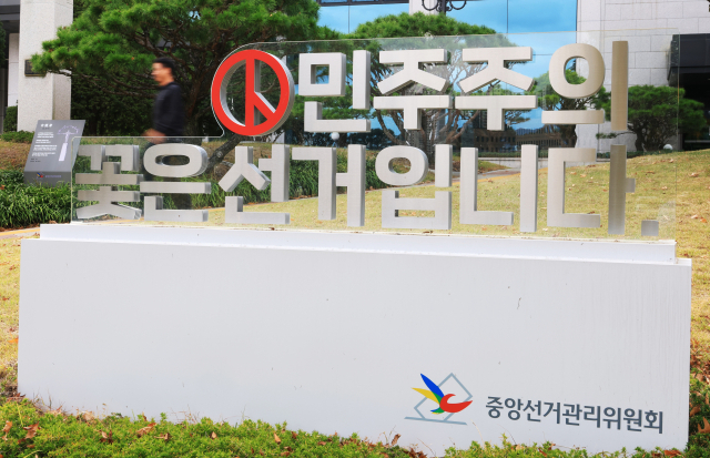 이태한 선거관리위원회 특별검사팀이 중앙선거관리위원회가 시간대별 투표자 수를 허위로 입력한 사실을 확인해 중앙선관위 등 7곳을 대상으로 압수수색에 들어간 15일 과천 중앙선관위에서 한 시민이 조형물 앞을 지나고 있다. 연합뉴스
