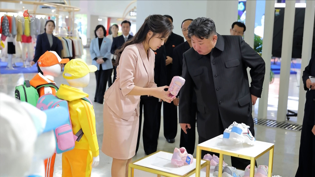 김정은 국무위원장이 지난 19일 '전국피복, 신발전시회-2026'을 찾아 딸 주애가 들어 보이는 분홍색 아동용 운동화를 살펴보고 있다. 조선중앙TV 화면. 연합뉴스