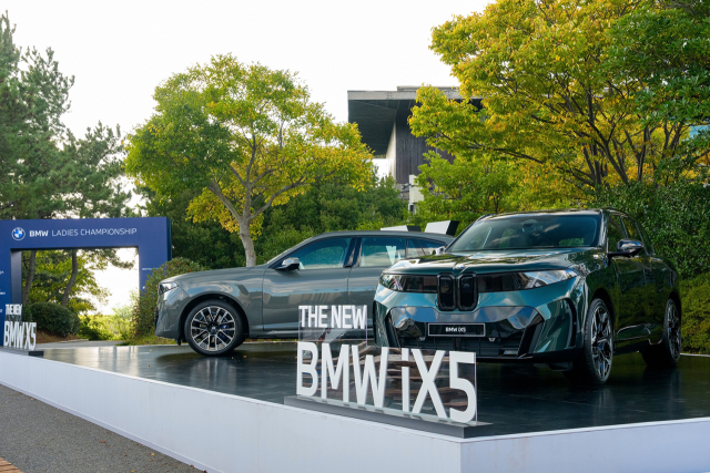 ‘BMW 레이디스 챔피언십 2026’이 열리고 있는 전남광주 해남 파인비치 골프링크스 내 갤러리 플라자에 전시돼 있는 가솔린 모델 ‘더 뉴 BMW X5(왼쪽)’와 순수전기차 ‘더 뉴 BMW iX5’.BMW코리아 제공