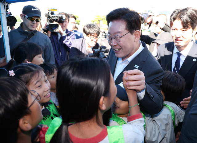 이재명 대통령이 22일 전북 익산 왕궁초등학교에서 열린 가을 체육한마당에서 학생들과 인사하고 있다. 연합뉴스